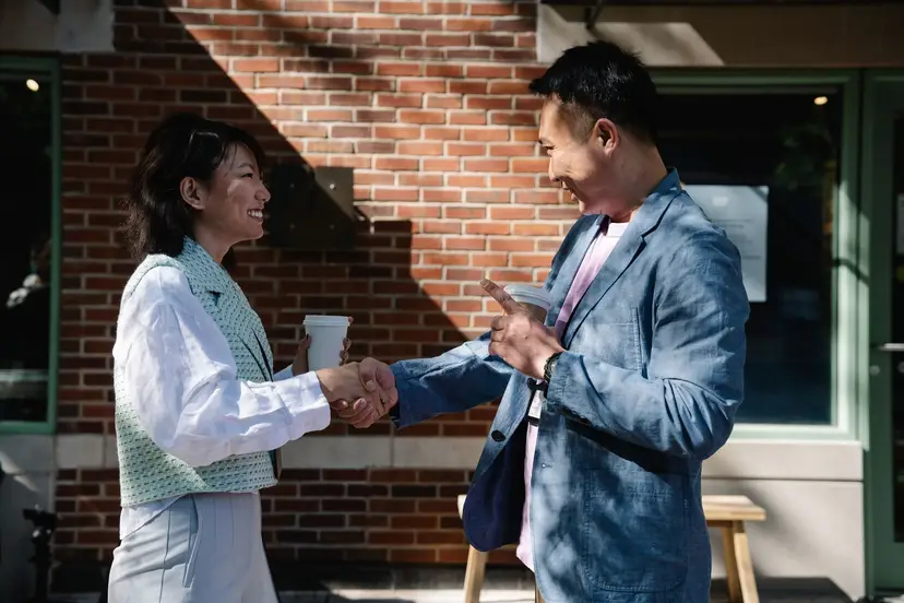 Two people shaking hands outside a brick storefront